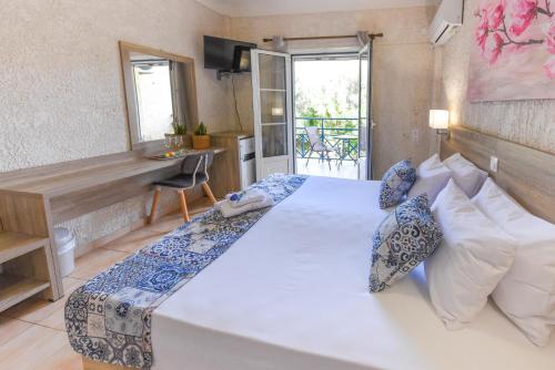 a bedroom with a large white bed and a desk at Paradise Hotel in Samos