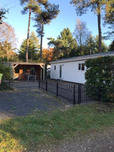 a home with a fence and a house at Chalet Bosrand 42 Park Veluwshof 6 p in Hoenderloo