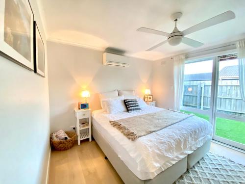 una camera da letto bianca con un letto e una finestra di Rosebud Lovely House - Mornington Peninsula 3 BR holiday house - Jacuzzi - BBQ - Basketball ring - Beach - Hot springs a Rosebud