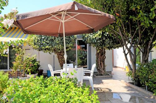 un tavolo e sedie sotto un ombrellone in giardino di Riverside Apartments Chiara a Ulcinj