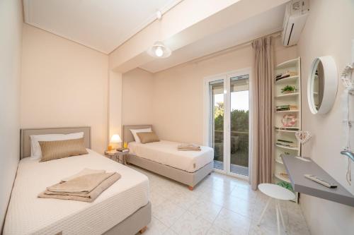 a white bedroom with two beds and a window at Dimitra Apartments & Studios in Minia