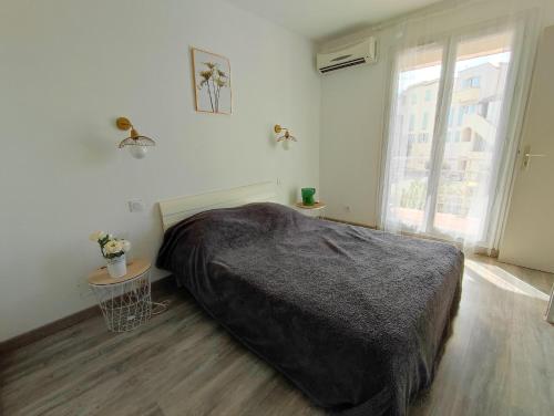 a bedroom with a large bed and a window at Casa Flamingo - Appartement calme et moderne - 4 - in Canet-en-Roussillon