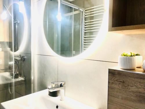 La salle de bains est pourvue d'un lavabo et d'un miroir. dans l'établissement Syrenka apartament, à Darłowo