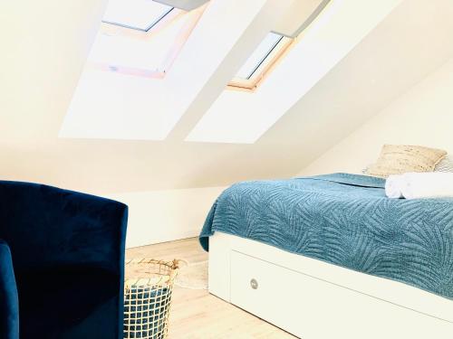 a attic bedroom with a bed and a chair at Syrenka apartament in Darłowo
