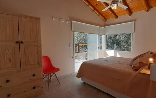 1 dormitorio con 1 cama y 1 silla roja en COSTA COM Departamentos de Montaña en Merlo