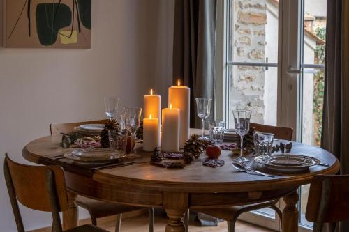 mesa de comedor con velas, platos y sillas en Domaine des Pousses, Chambres d'hôtes au coeur d'un village de campagne en Droue-sur-Drouette