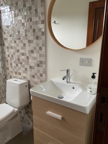 een badkamer met een wastafel, een toilet en een spiegel bij Apartamento El Nogal 1 in Tui