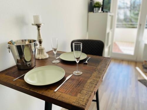 a wooden table with two plates and wine glasses at Bike Hike Ski Brilon - Ferienappartment in Brilon