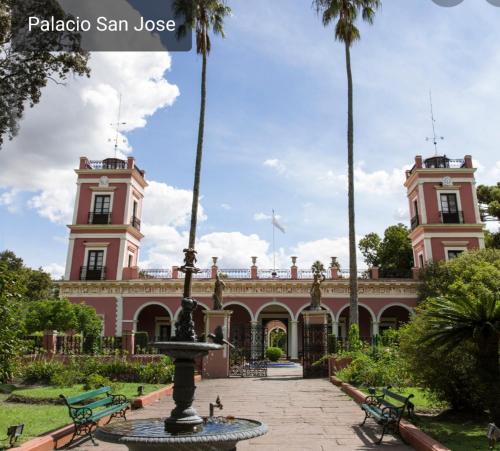 un edificio rosa con una fuente frente a él en Edificio La Vieja Casona, en Concepción del Uruguay