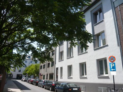 a white building with cars parked on the side of a street at Koelsche Kluengel in Cologne
