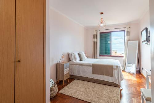 een witte slaapkamer met een bed en een raam bij Bela Vista in Caniço