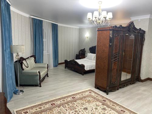 a room with a bedroom with a bed and a chair at Hotel Astam in Kostanay