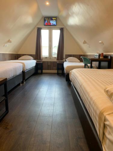 a room with three beds and a tv on the wall at Dam Hotel in Amsterdam