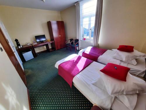 a hotel room with two beds with red pillows at Hotel Le Monte Cristo in Mons