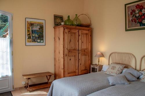 1 dormitorio con 1 cama y armario de madera en Le Clos des Oliviers, en Le Rouret