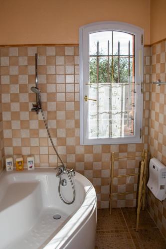 une baignoire dans une salle de bain avec une fenêtre dans l'établissement Le Clos des Oliviers, à Le Rouret