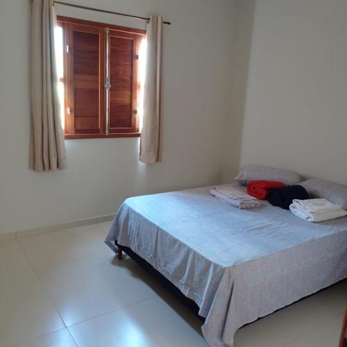 a bed in a white room with a window at Agradável Casa de Campo, recém construída. in Divisa