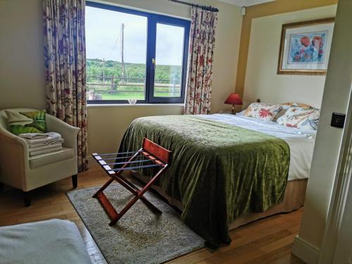 um quarto com uma cama, uma cadeira e uma janela em The Ferris Wheel B&B em Beaufort