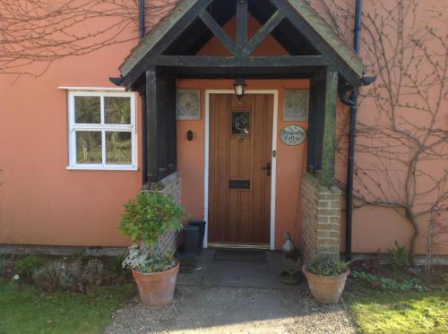 a orange house with a wooden door and a window at Dragonfly Cottage, Rattlesden in Rattlesden