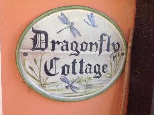 Un cartello su un muro con delle farfalle blu sopra. di Dragonfly Cottage, Rattlesden a Rattlesden