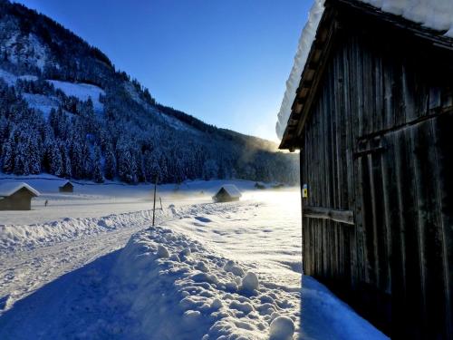 a snow covered field next to a barn at Appartment Almenliesl in Gosau
