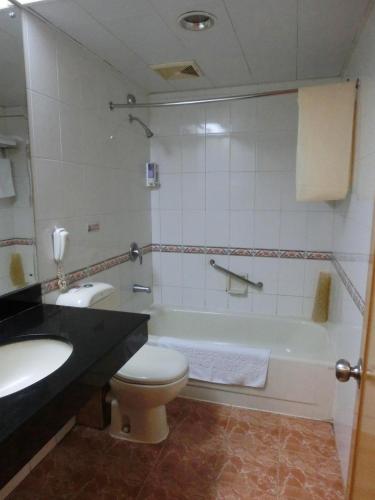 a bathroom with a toilet and a sink and a tub at New Asia Hotel in Guangzhou