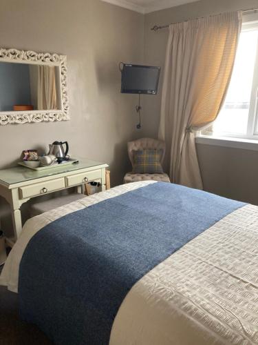 a bedroom with a bed and a desk and a mirror at Twenty Seven in Stornoway