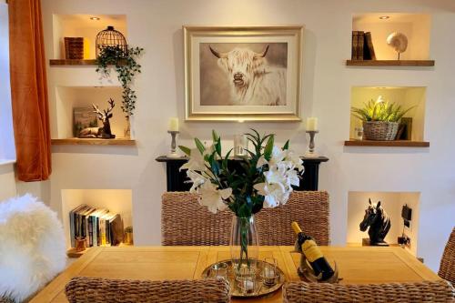 a dining room table with a vase of flowers on it at Renovated Miner’s Cottage - family & dog friendly in Abertillery
