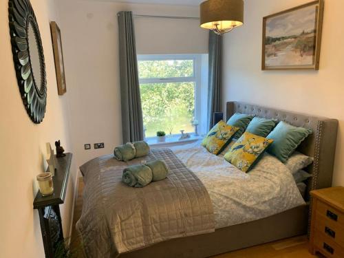 a bedroom with a bed with pillows and a window at Renovated Miner’s Cottage - family & dog friendly in Abertillery