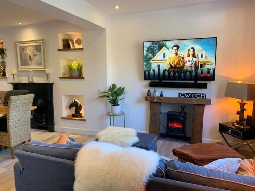 a living room with a couch and a tv at Renovated Miner’s Cottage - family & dog friendly in Abertillery