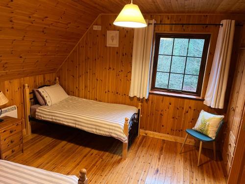 sypialnia z 2 łóżkami w drewnianym domku w obiekcie Cosy Lakeside Chalet With Option to add Private Hot Tub & Boat w mieście Duneena