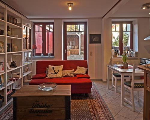 a living room with a red couch and a table at Gemütliches Ferienhaus - ankommen und wohlfühlen in Husum