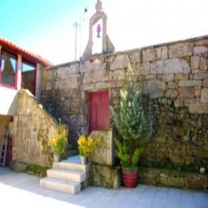 a stone building with a red door and some plants at Casa Do Seminario in Gralhas