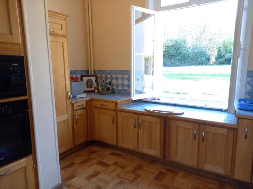 a kitchen with a large window and wooden cabinets at Gîte Chateau baie de somme 10 a 12 personnes in Mons-Boubert