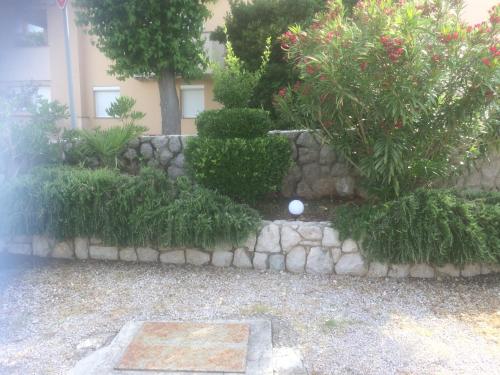 a garden with a stone wall and trees and flowers at Botic Apartments in Šilo