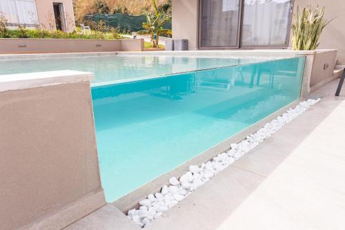 a pool with blue water and white rocks around it at Twins Apartments in Platanias