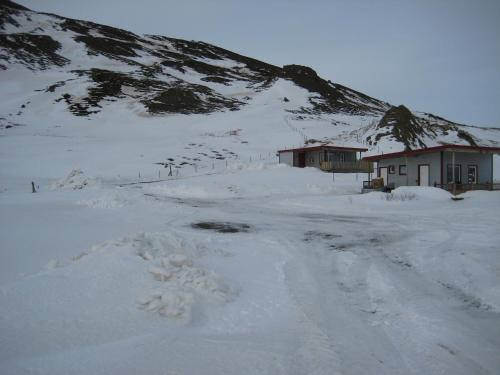 a road covered in snow next to a mountain at Ásbrandsstadir Cottages in Vopnafjörður