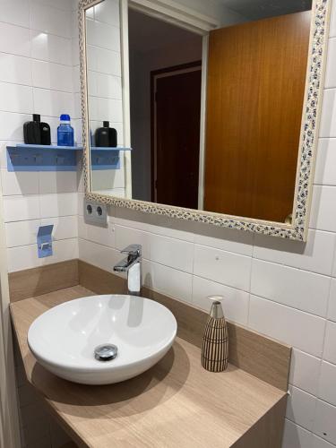 uma casa de banho com um lavatório branco e um espelho. em Sa Calma em Tossa de Mar