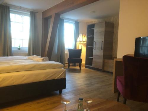 a hotel room with a bed and a chair at Landhotel Gutshof im Oertzetal in Oldendorf, Südheide in Hermannsburg