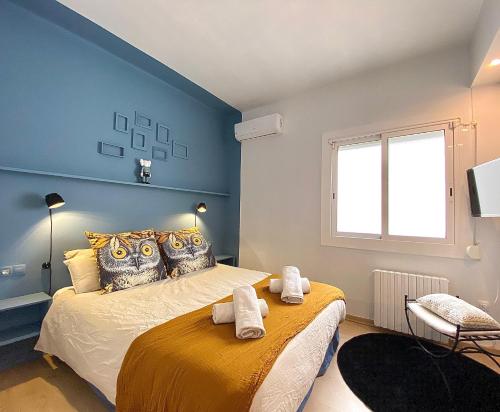 ein Schlafzimmer mit blauen Wänden und ein Bett mit Handtüchern drauf in der Unterkunft Abbott apartment old town - 1 min from the beach in Sitges
