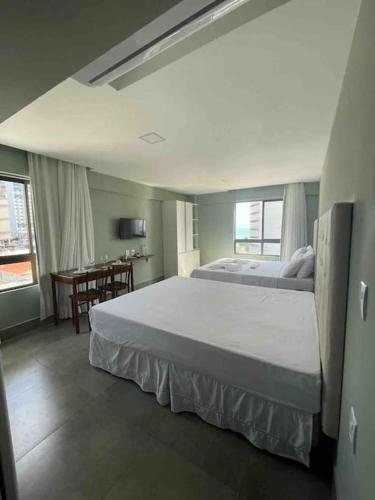 a bedroom with a large white bed and a desk at Ilusion flat Ponta Negra in Natal