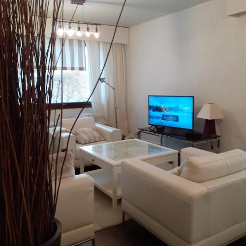 a living room with white furniture and a tv at Lohja Lempola 2 room apartment in Lohja