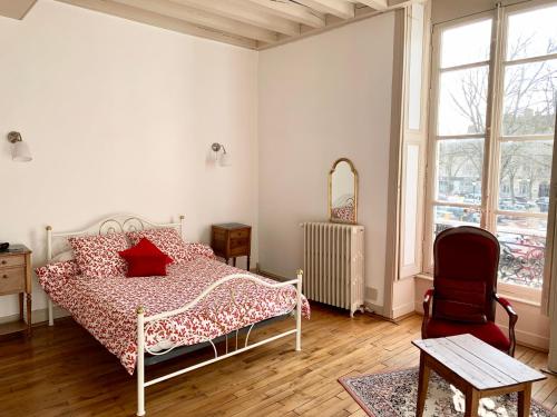 a bedroom with a bed and a chair and windows at Le Relais Dunois de Napoléon in Châteaudun