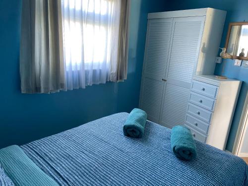 a blue bedroom with a bed with two blue towels on it at Driftwood WINTERTON VALLEY ESTATE Dog Friendly in Winterton-on-Sea