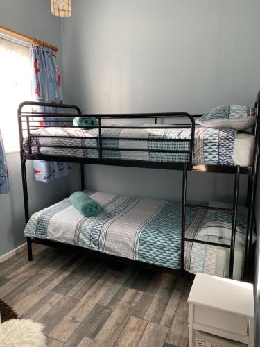 two bunk beds in a room with a wooden floor at Driftwood WINTERTON VALLEY ESTATE Dog Friendly in Winterton-on-Sea