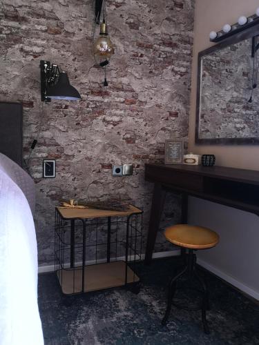 a bedroom with a table and a stool in front of a brick wall at Casa Segota in Veli Iž