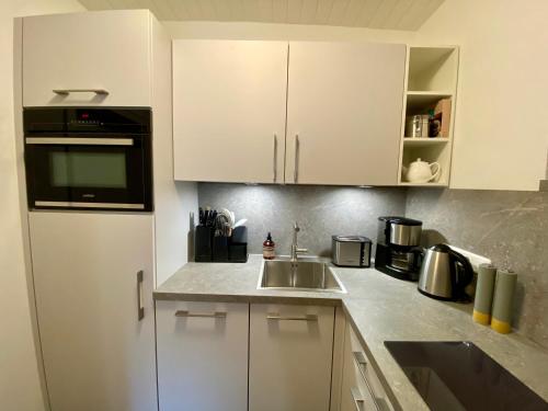 a kitchen with white cabinets and a sink at Ferienwohnung an der idyllischen Salzachschleife Nähe Salzburg in Laufen