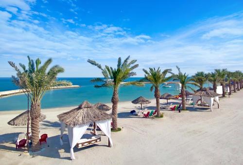 una playa con palmeras, sombrillas y el océano en Jaw Resort & Spa, en Jaww