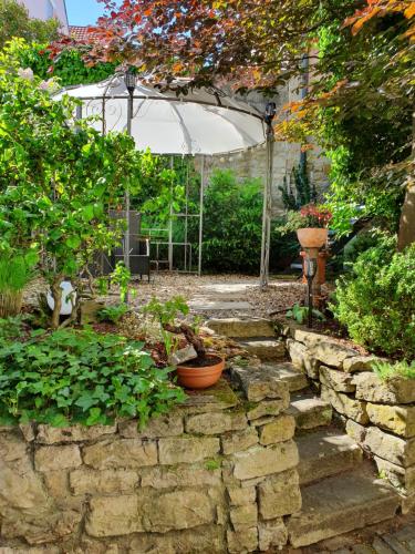 a garden with a stone wall and a white tent at Hotel & Restaurant Sonnenhöfle in Sommerhausen