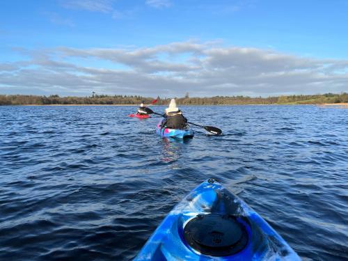 two people in kayaks on a large body of water at Cosy Lakeside Chalet With Option to add Private Hot Tub in Duneena
